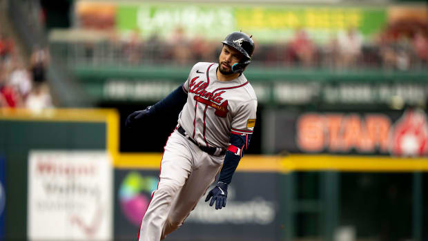 Atlanta Braves catcher Travis d'Arnaud (16) looks at the Atlanta Braves dugout as he rounds third base after hitting a 3-run home run in the first inning of the MLB baseball game between the Cincinnati Reds and the Atlanta Braves at Great American Ball Park in Cincinnati on Friday, June 23, 2023.